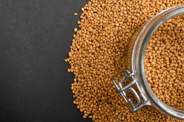 grains for brewing buckwheat tea in a jar and scattered on a black background