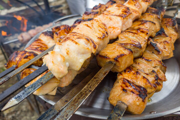 Grilled salmon fish kebab skewers on wooden board. Dark wooden background.