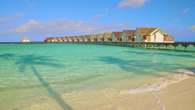 Sandy beach on a tropical Maldives island leading to luxury overwater bungalows