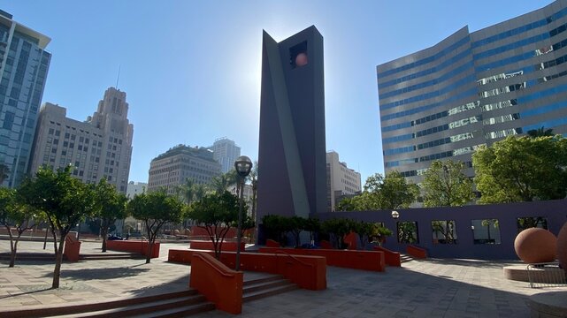 LOS ANGELES, CA, AUG 2021: Pershing Square in Downtown with sun backlighting purple concrete, sculptural piece and tall buildings in background