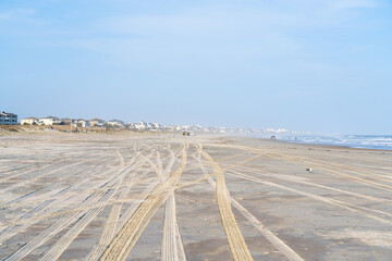 Large beach with tire tracks in the sand from four wheel drive vehicles