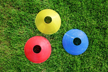 Top view of colorful border cones on the green grass prepared for training in kids football academy. Health and active lifestyle. Popular sport activity