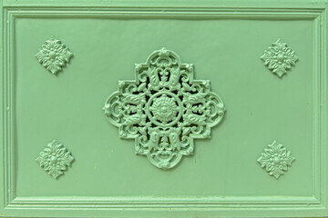 Rosette decoration on an old light green iron cast door, detail of an old grave monument