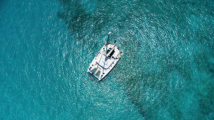 Beautiful sailing catamaran at anchor. Aerial view of a yacht in clear turquoise water in the...