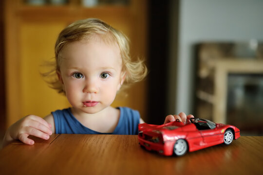 Cute toddler boy playing with colourful toy cars at home.