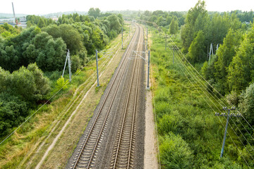 Beautiful top down aerial view of railroad tracks. Railroad tracks surrounded by green vegetation of countryside.