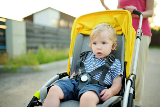 Sweet toddler boy sitting in a stroller outdoors. Little child in pram. Infant kid in pushchair. Summer walks with kids.