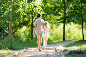 Two sisters on tactile path in barefoot park created to feel the ground and other materials with bare feet. Strengthen foot and leg muscles by walking on uneven surface.