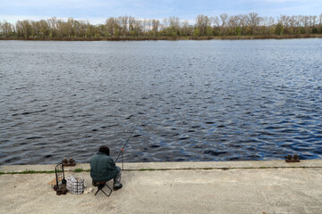 Obraz na płótnie Canvas Fisherman with a fishing rod on the river bank