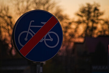 Znak drogowy ; " koniec drogi dla rowerów " , na tle ciemnego nieba podczas zachodu słońca .