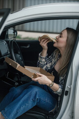 a young beautiful woman has lunch in the car with ready-made, purchased food, eats pizza with appetite and pleasure