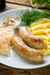 bavarian sausages with mashed potatoes and mustard on white plate on wooden table macro close up