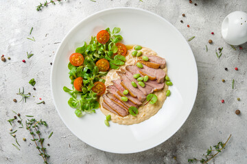 Sliced Duck breast with vegetables and risotto top view
