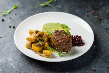 grilled steak filet Mignon with fried baby potatoes and onion jam on white plate
