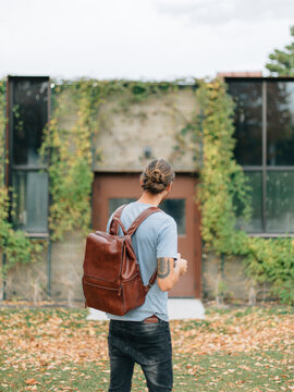 young man with man bun standing in front of old building with vi