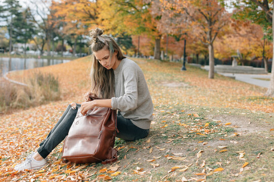 woman wearing neutral colors sitting outside in the fall looking