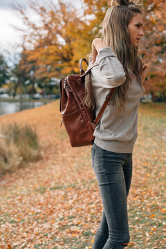 woman adjusting backpack outside in the fall surrounded by orang