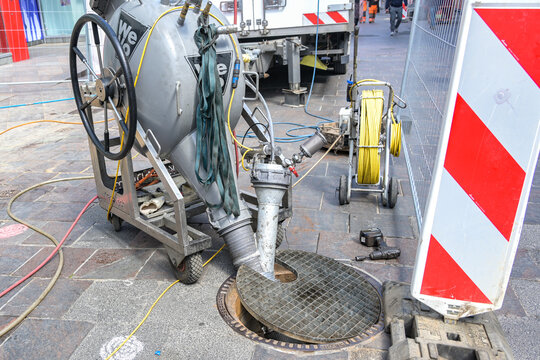 Lubeck, Germany, May 4, 2022: Sewer works with a pumping machine and big hoses at a manhole in a city street, professional technology on a construction site