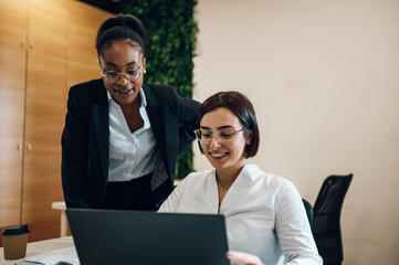 Two multiracial businesswoman working together in an open space office