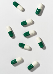 Green and white pills on white background