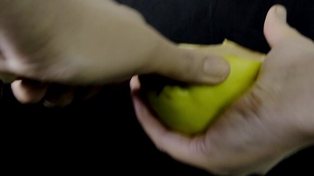 Cutting a slice of yellow green quince with a knife in the hand