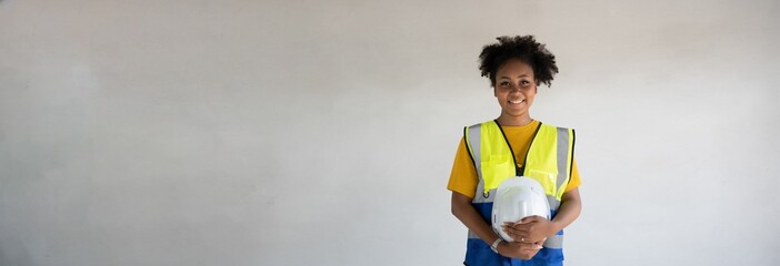 
Portrait of a beautiful female Expert engineer with black African American skin.Attractive woman worker holding hard hat wearing reflective vest with Free,Copy space,  wall,banner,cover,design,PPE.