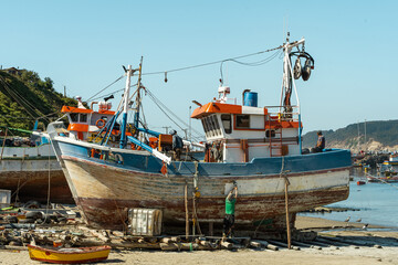 Vertical shot of boats under repair in Caleta Tumbes with beach and small boats below, Chile