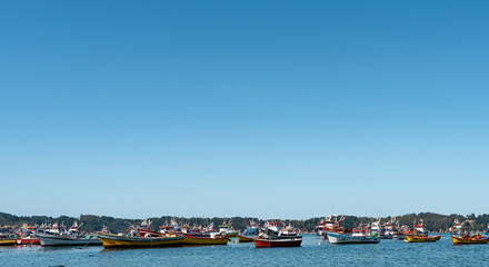 Fototapeta na wymiar Horizontal shot of colorful boats in Caleta Tumbes with wide sky in the background, Chile