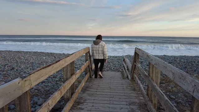 Young Woman Walking on Beachfront Boardwalk
