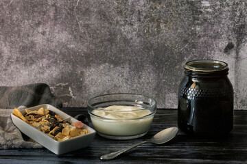 Jar of natural honey and freshly made homemade yogurt next to a container of nuts