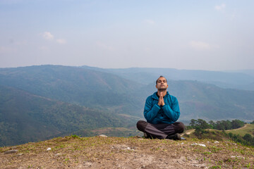 man meditating at hill top with misty mountain rage background from flat angle