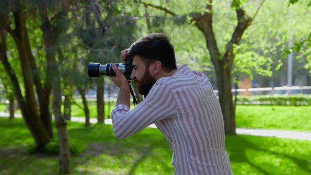 Portrait of a young photographer with a camera standing in nature. Photographer taking pictures.