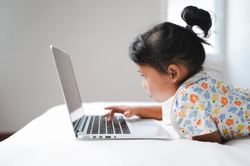 Cute little girl typing on notebook keyboard. Online learning, home school.