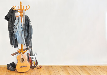 The rocker's clothes hanging on a hanger with guitar on a floor