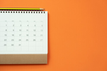 close up of calendar and pencil on the orange table background, planning for business meeting or travel planning concept