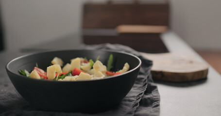 hard cheese on cherry tomatoes and fresh arugula in black bowl on concrete countertop