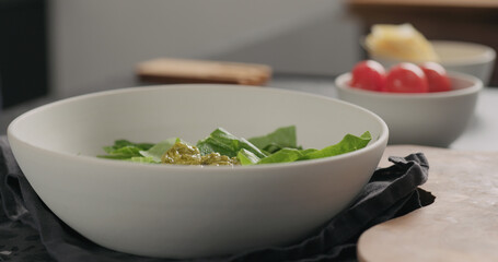 put pesto over romaine lettuce in white bowl