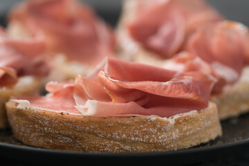 bruschetta with prosciutto and cream cheese on black plate closeup