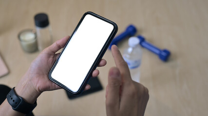 Fototapeta premium Closeup view of woman sitting on mat and using smart phone, resting from exercises at home.