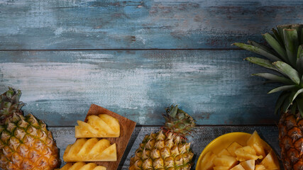 Whole and sliced tropical pineapple on wooden background with copy space.