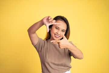 young woman looking at the camera from between fingers forming a frame on isolated background