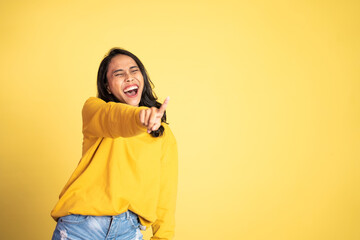 beautiful woman with finger pointing at frong and laughing at something isolated background