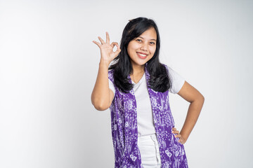 Young woman smiling with okay hand gesture on isolated background