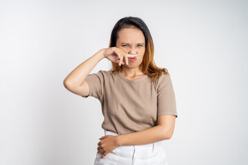 Young asian woman covering nose with finger when bad smell on isolated background