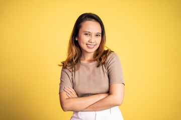 Fototapeta premium attractive asian ethnicity female looking at camera smiling with crossed arm on isolated background