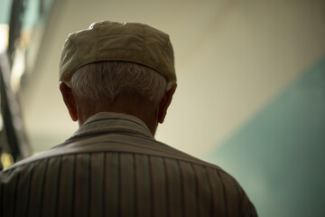 Old man from behind. Man in cap in entrance of apartment building.