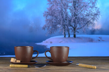Two cups of tea on background of a winter landscape
