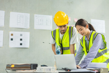 Professional of team Asian engineers and  foreman in helmets working meeting with blueprint and construction tools on table at the construction site.