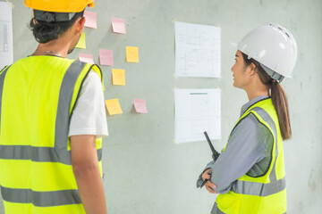 Professional of team Asian engineers and  foreman in helmets working meeting with blueprint and construction tools on table at the construction site.