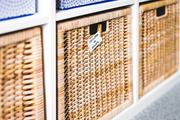 decluttering and tidying up concept, basket with Declutter or Donate label on it with unfocused storage cabinet and other baskets in the background